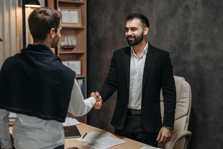 Two businessmen shaking hands in a modern office, sealing a business deal.